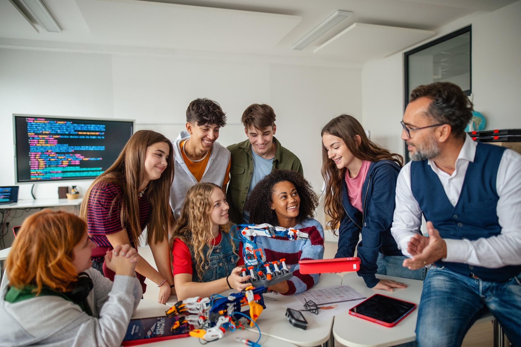 Teacher and students examining a small robot together