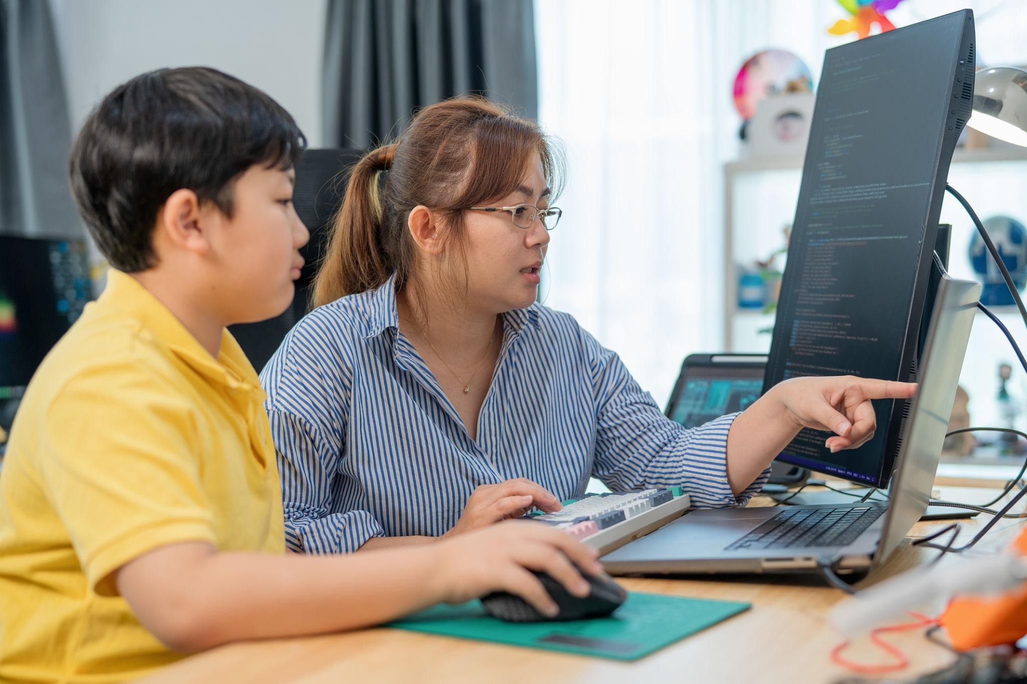 Students working on laptops in a coding environment